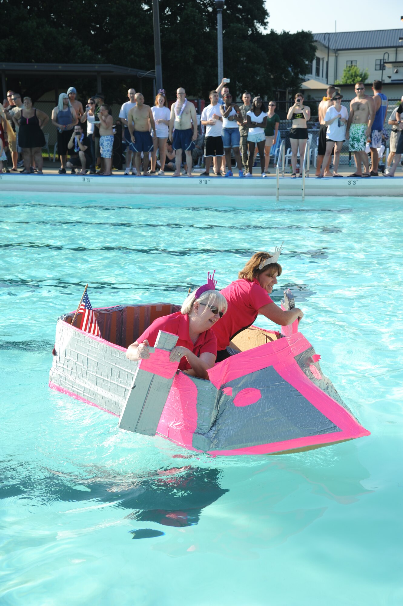 Jackie Pope and Lisa Lyons, 81st Force Support Squadron, paddle their vessel, The Return of the Airman and Family Readiness Center Unsinkables, to the finish line during the cardboard boat regatta June 15, 2013, at the Triangle Pool, Keesler Air Force Base, Miss.  Their boat took first place in the event with a time of three minutes.  (U.S. Air Force photo by Kemberly Groue)