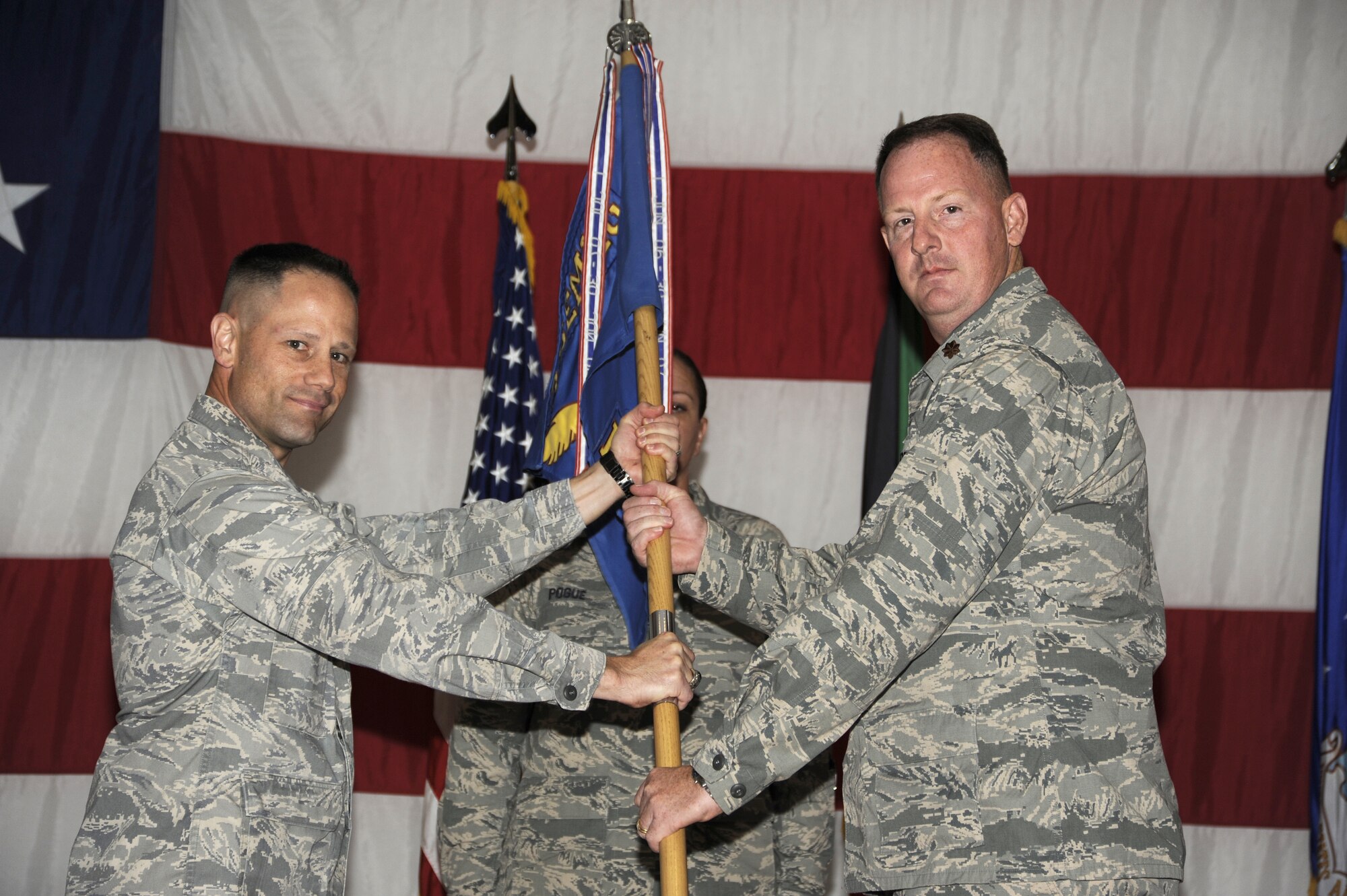 Colonel Michael M. O'Connor,386th Expeditionary Maintenance Group commander, left, passes the 386th Expeditionary Maintenance Squadron guidon to Maj. Robert Custer during a change of command ceremony at an undislosed location in Southwest Asia June 17. Custer assumed command of the 386th EMXS from Maj.Andrew M. Garcia (U.S. Air Force photo by Master Sgt. Christopher A. Campbell)