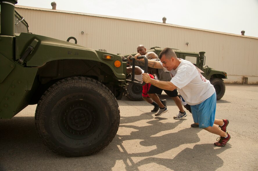 Tech. Sgt. Jesus Olivares, 8th Civil Engineer Squadron dorm manager, along with teammates push their way through the fifth obstacle of the Wolf Pack Warrior Mud Run at Kunsan Air Base, Republic of Korea, June 8, 2013. Each team pushed a Humvee from one end of the parking lot to another. (U.S. Air Force photo by Senior Airman Jessica Haas/ Released)
