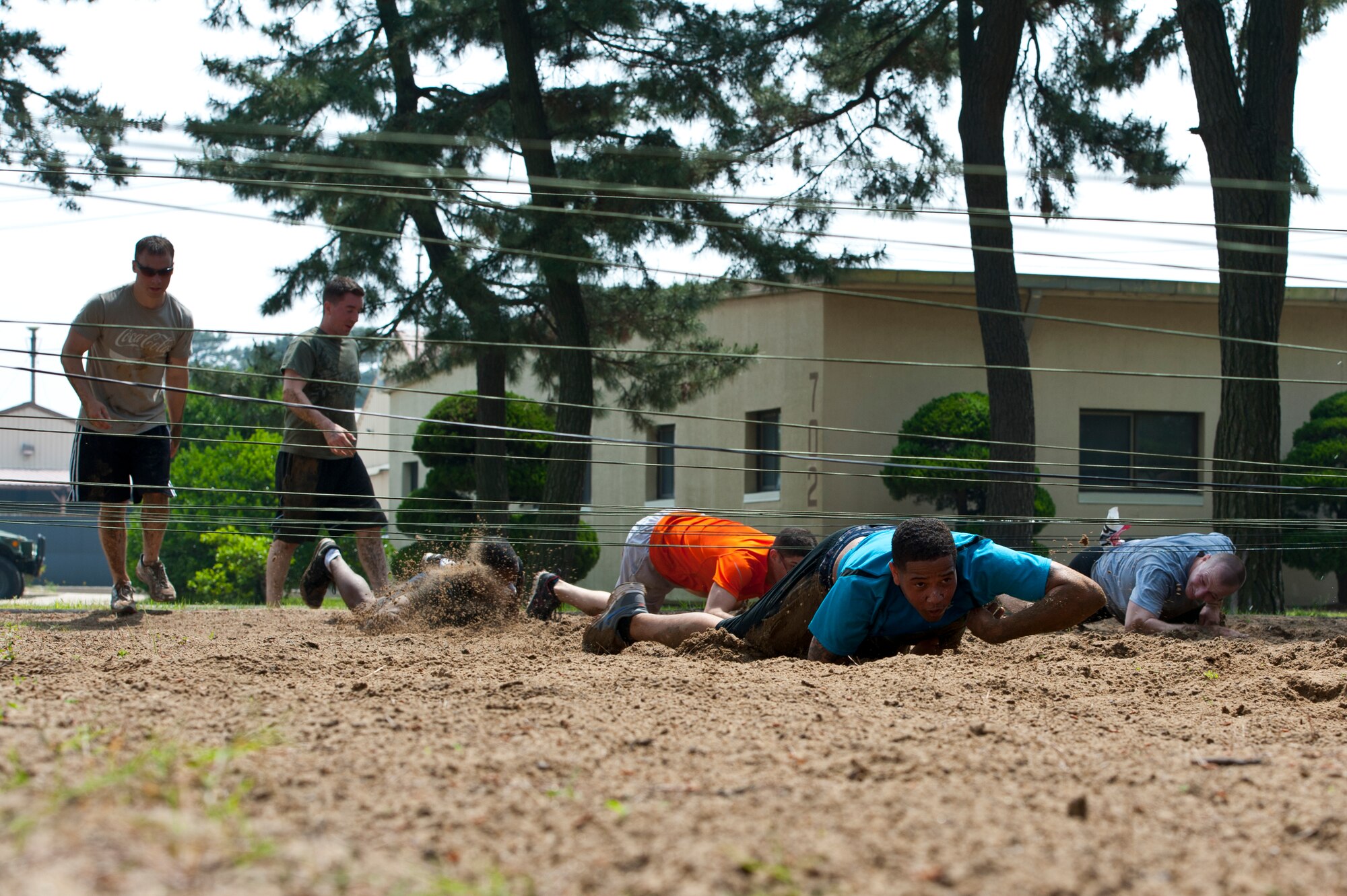 8th Fighter Wing Airmen low crawl through mud and sand during the Wolf Pack Warrior Mud Run at Kunsan Air Base, Republic of Korea, June 8, 2013. The 1.88 mile course featured a number of low crawl obstacles, Humvee push, Air Force history questions and a ‘slip and slide’ finish. (U.S. Air Force photo by Staff Sgt. Jonathan Fowler/Released)