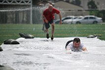 Col. S. Clinton Hinote, 8th Fighter Wing commander, dives through the ‘slip and slide’ obstacle of the Wolf Pack Warrior Mud Run followed closely by Maj. Shawn McGoffin, 8th Fighter Wing director of staff, at Kunsan Air Base, Republic of Korea, June 8, 2013. More than 35, four-person teams participated in the mud run which honored 1st Lt. Josh Hovies, who passed in April, 2013. (U.S. Air Force photo by Senior Airman Clayton Lenhardt/Released)