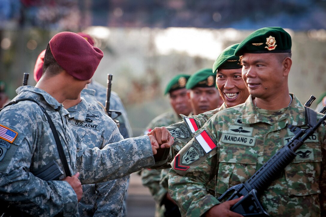 Indonesian and U.S. Army paratroopers bump fists in a show of friendship before the opening ceremony of Garuda Shield 2013 bilaterial training at 1st Kostrad Headquarters, West Java, Indonesia, June 10, 2013.