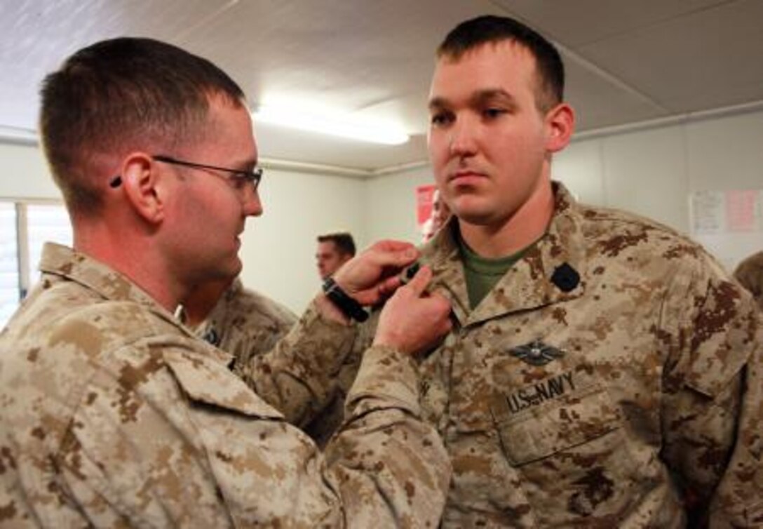 Petty Officer 2nd Class Tyler Adkerson (left), senior line corpsman, Lima Company, 3rd Battalion, 3rd Marine Regiment, Marine Rotational Force – Darwin, pins on the rank insignia of newly promoted Petty Officer 2nd Class Nathan Hatton (right), corpsman, Lima Co., 3rd Bn., 3rd Marine Regiment, MRF-D, during a promotion formation and a US Navy Hospital Corps birthday celebration, here, June 17. This birthday marks 115 years of the US Navy Hospital Corps.
