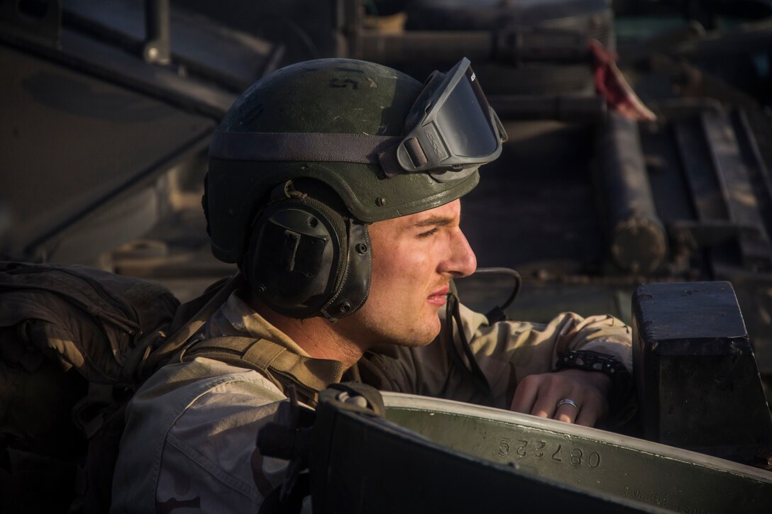 Ensign Ethan Strauser, USS Carter Hall gunnery officer from Chesapeake, Va., rides in the troop commander hatch of an amphibious assault vehicle (AAV) assigned to AAV Platoon, Battalion Landing Team 3/2, 26th Marine Expeditionary Unit (MEU), during Exercise Eager Lion 2013 in Al Quweira, Jordan, June10, 2013. Exercise Eager Lion 2013 is an annual, multinational exercise designed to strengthen military-to-military relationships and enhance security and stability in the region by responding to realistic, modern-day security scenarios. The 26th MEU is a Marine Air-Ground Task Force forward-deployed to the U.S. 5th Fleet area of responsibility aboard the Kearsarge Amphibious Ready Group serving as a sea-based, expeditionary crisis response force capable of conducting amphibious operations across the full range of military operations. (U.S. Marine Corps photo by Cpl. Michael S. Lockett/Released)