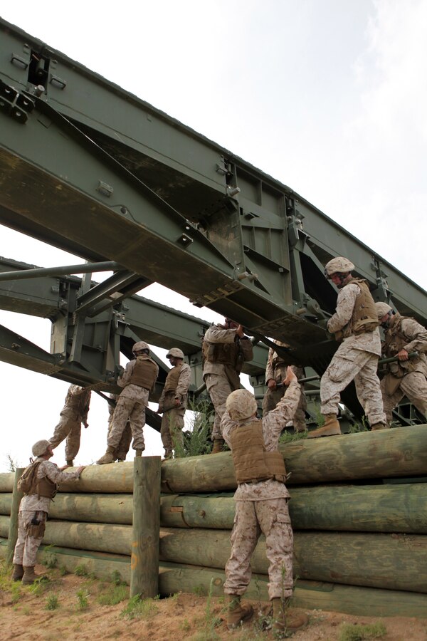 BATTLE CREEK, Mich. – Marines with 6th Engineer Support Battalion make adjustments to the underside of a medium girder bridge during a training exercise here, June 11. The base of the bridge must be able to hold massive amounts of weight when it is used to create routes across impassable terrain.