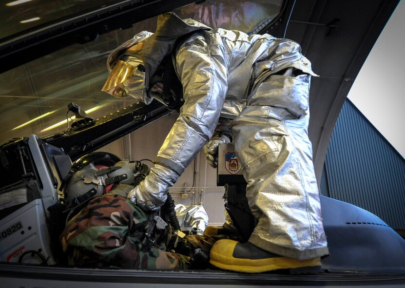 A firefighter from the 35th Civil Engineer Squadron helps a simulated pilot egress from an F-16 Fighting Falcon during an Operational Readiness Exercise at Misawa Air Base, Japan, June 18, 2013. The scenario simulated smoke in the cockpit and an unconscious pilot. (U.S. Air Force photo by Staff Sgt. Nathan Lipscomb)