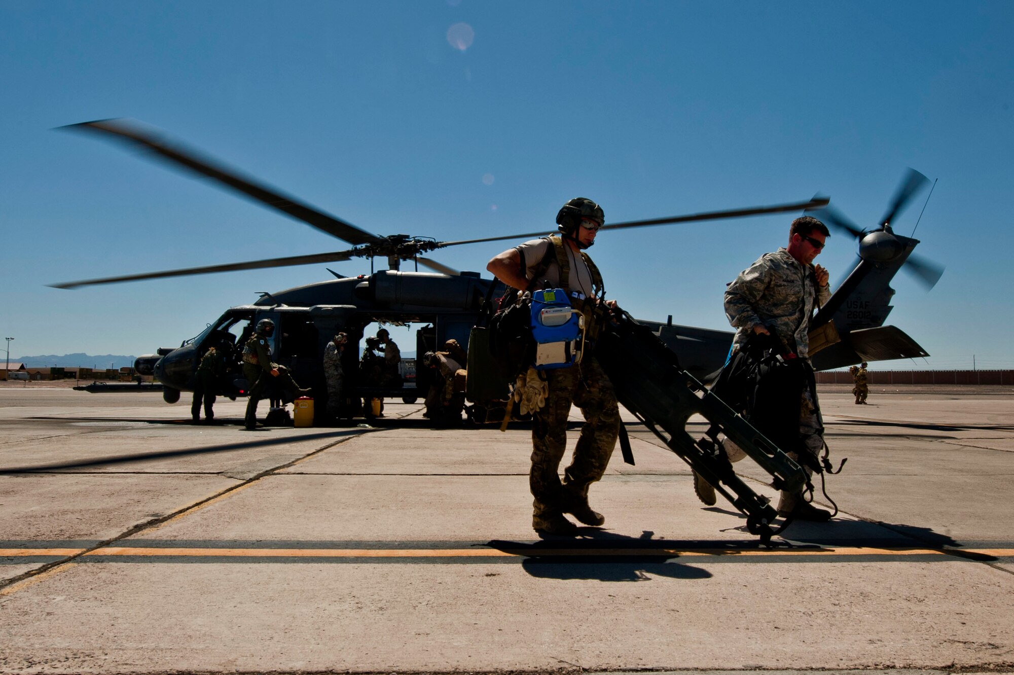 A Pararescueman and a Combat Rescue Officer from the 58th Rescue Squadron carry gear used in a search and rescue mission in California June 14, 2013, after returning to Nellis Air Force Base, Nev. After rescuing the lost hiker, AF Rescue Flight and Rescue Team recovered to Bishop International Airport where medical teams were waiting to transport the hiker to a local hospital. (U.S. Air Force photo by Senior Airman Daniel Hughes)