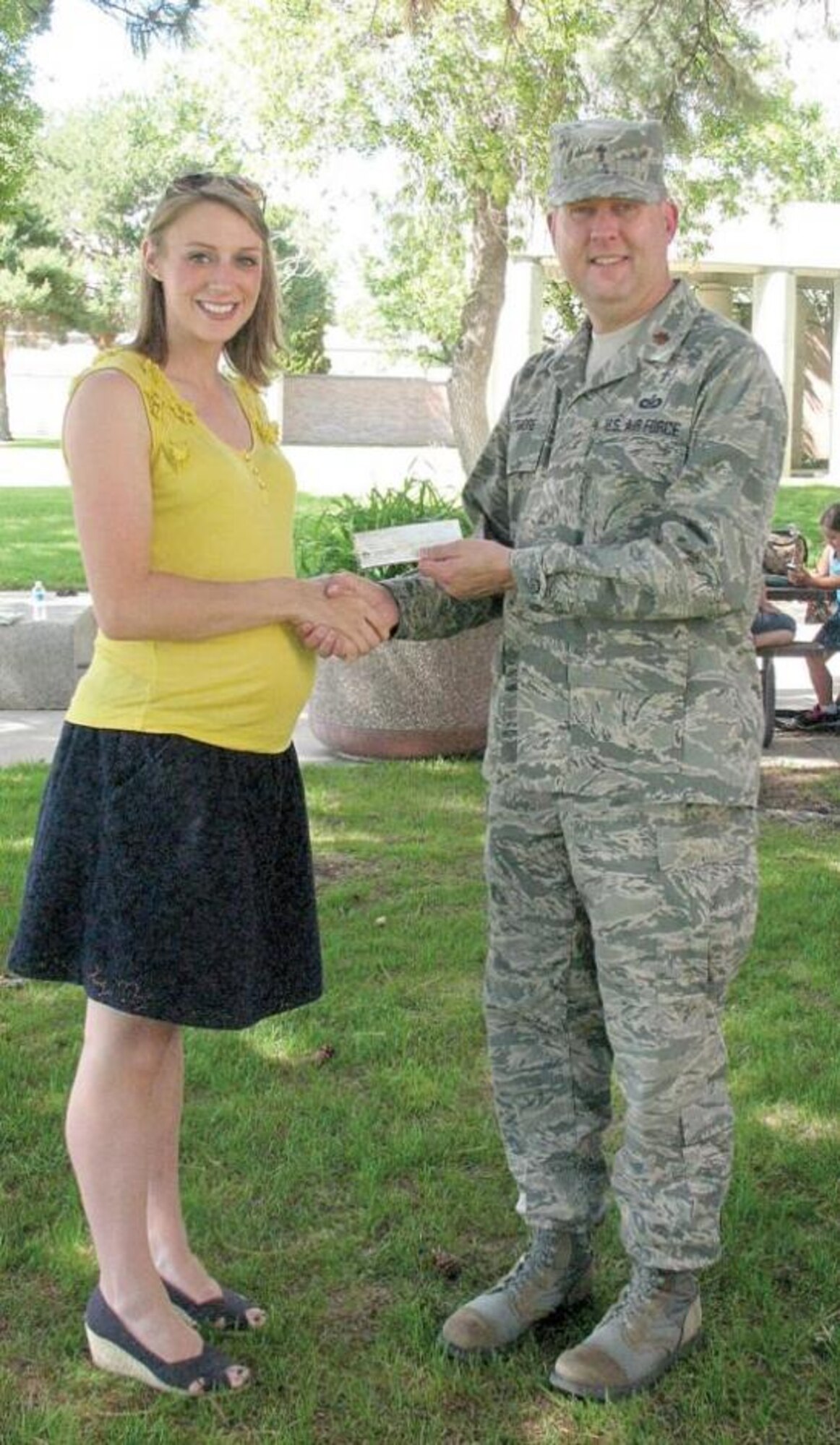 Vania Ferreira presents a check of $2,200 to Chaplain (Maj.) Eric Whitmore. Vania and her family enjoyed a recent  AEF (Air Expeditionary Forces) retreat so much that when she received funds as the result of her appearance on the Ellen DeGeneres Show, she and her husband, 1st. Lt. Rob Ferreira, decided to make a contribution in support of the retreats. (Courtesy photo)