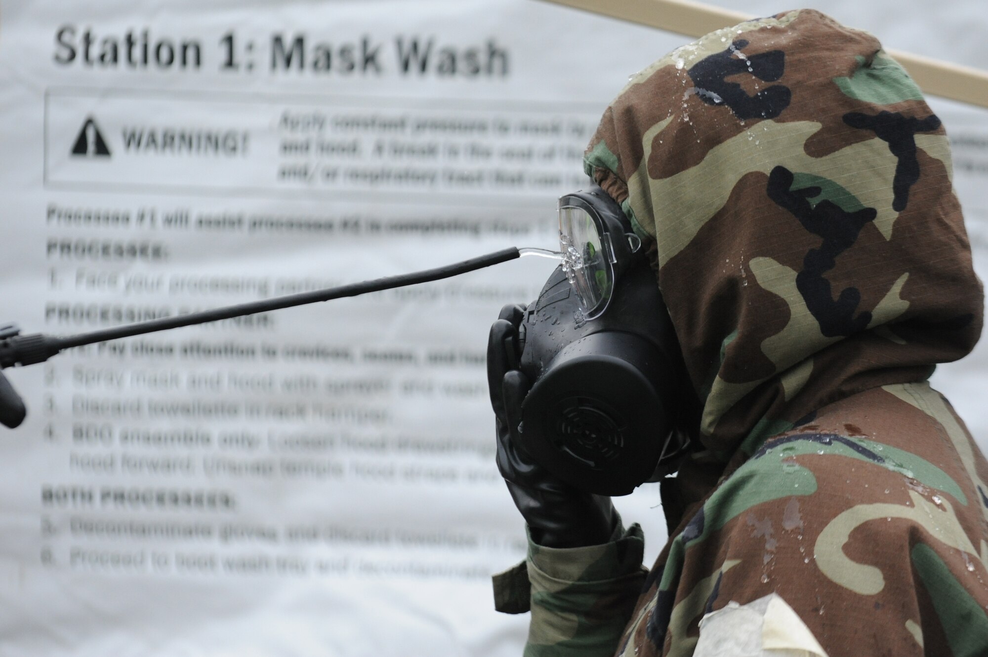 U.S. Air Force Airman Tyler Bryantt, 35th Communications Squadron, has his gas mask washed in a contamination control area during an Operational Readiness Exercise at Misawa Air Base, Japan, June 18, 2013. The mask wash station was one of four stations that Airmen were required to pass through to fully remove simulated chemical contamination. (U.S. Air Force photo by Senior Airman Derek VanHorn)