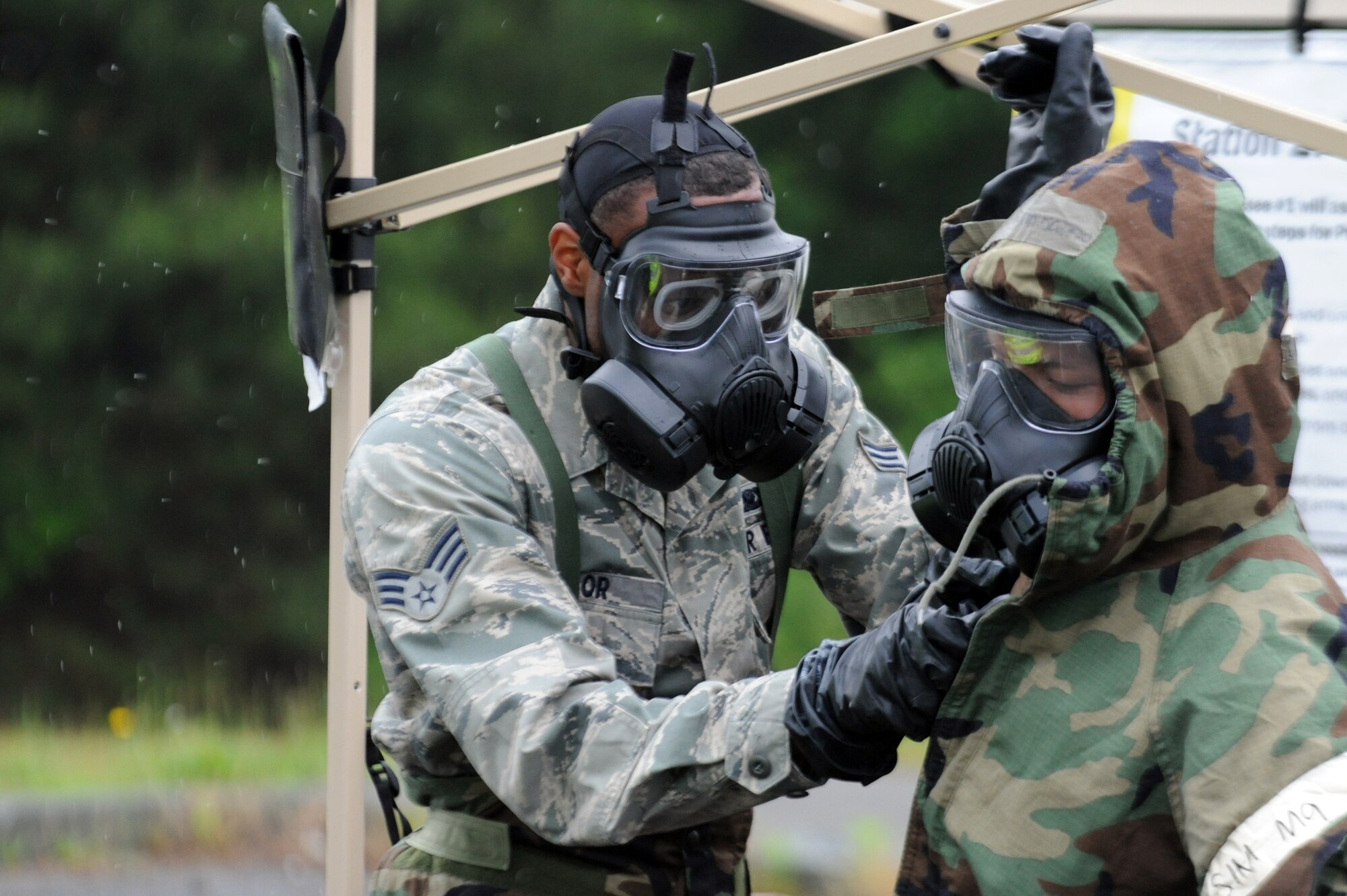 U.S. Air Force Senior Airman Kenneth Taylor, 35th Aircraft Maintenance Squadron, removes protective over garment equipment from Staff Sgt. Alpheus Escudero, 35th Maintenance Group, while passing through a contamination control area during an Operational Readiness Exercise at Misawa Air Base, Japan, June 18, 2013. Airmen exposed to the hazards of biological or chemical agents decontaminate themselves by processing through a CCA as part of the week-long exercise. (U.S. Air Force photo by Senior Airman Derek VanHorn)