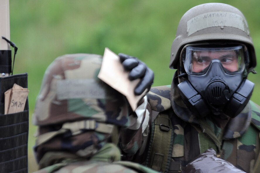 U.S. Air Force Airman 1st Class Nathan Kinsaul, 35th Maintenance Squadron, applies simulated decontamination paper to Airman 1st Class Victoria Benson, 35th Operations Support Squadron, during an Operational Readiness Exercise at Misawa Air Base, Japan, June 18, 2013. Following simulated chemical attacks, more than 25 Airmen decontaminated using four stations based within a contamination control area. (U.S. Air Force photo by Senior Airman Derek VanHorn)