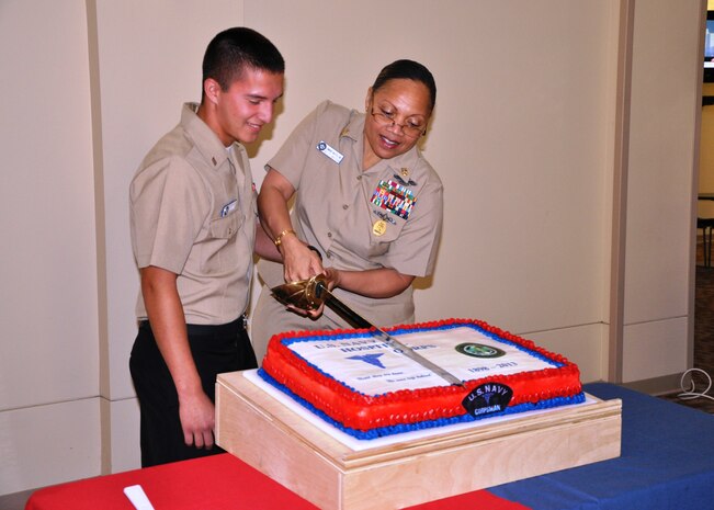 Master Chief Petty Officer Betty Watson and Seaman Austin Serna cut a birthday cake celebrating the 115th birthday of the U.S. Navy Hospital Corpsman rate June 14, 2013, in the atrium at Naval Health Clinic Charleston at Joint Base Charleston – Weapons Station, S.C. Watson and Serna are the oldest and youngest hospital corpsman at NHCC. The oldest and youngest traditionally cut the cake, a practice that represents the experience of veteran Sailors and the youth and energy of the future. (U.S. Navy Photo/Jeff Kelly)