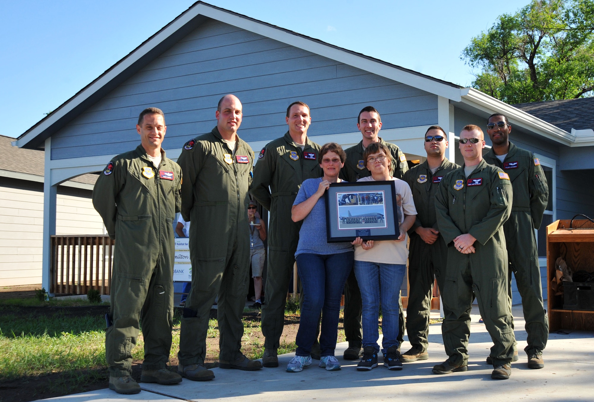 Airmen from the 350th Air Refueling Squadron, McConnell Air Force Base, Kan. and new home owner, Melissa, and her daughter, stand in front of the house they helped build, June 17, 2013, in Wichita, Kan. McConnell Airmen routinely volunteer with the Wichita Habitat for Humanity, a non-profit organization, that works in partnership with low-income families to improve their living conditions. (U.S. Air Force photo by Staff Sgt. Jess Lockoski)