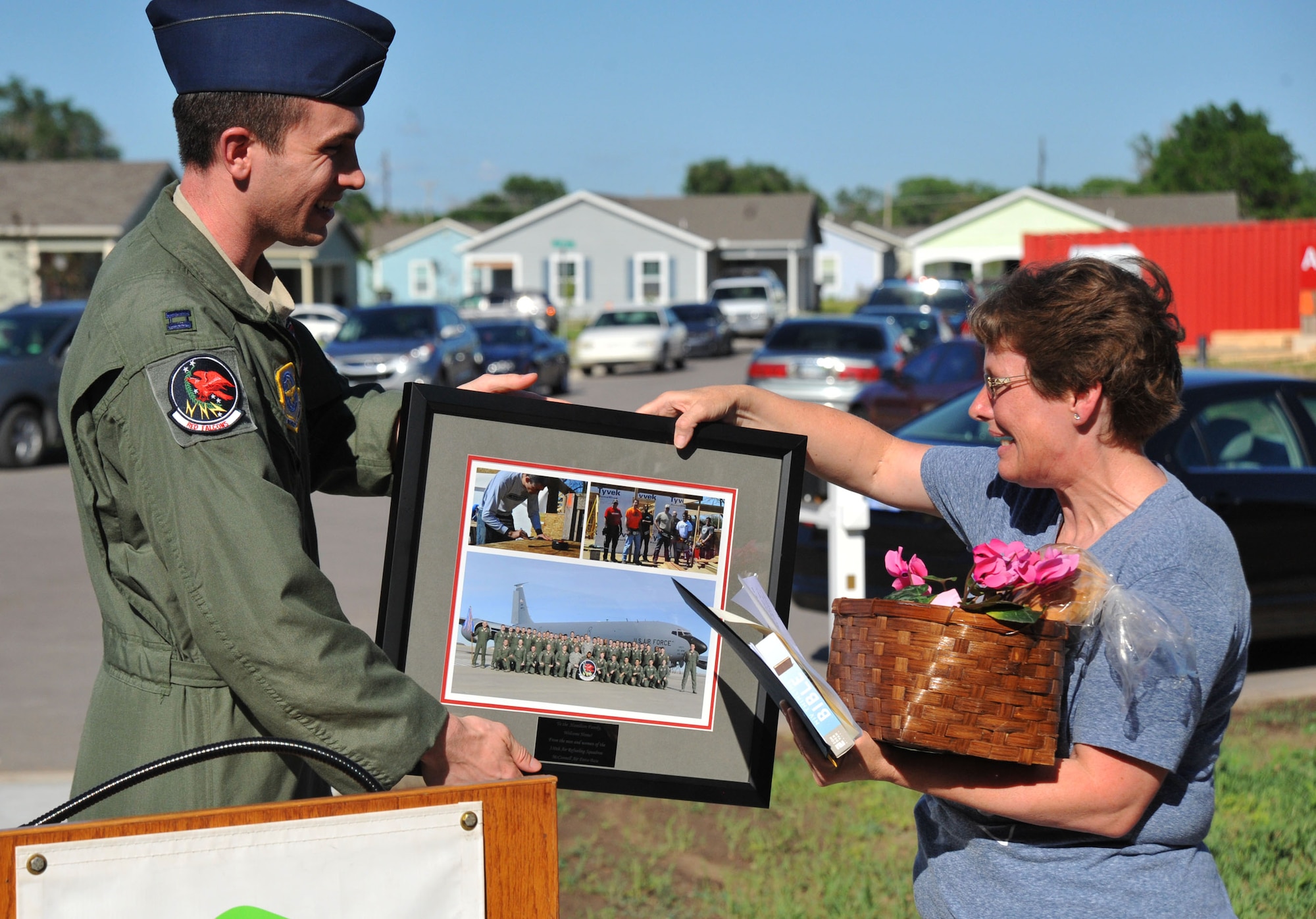 Capt. Nathaniel Delaney, 350th Air Refueling Squadron pilot, McConnell Air Force Base, Kan. presents Melissa, a new Habitat for Humanity home owner with a squadron photo, June 17, 2013, in front of her home in Wichita, Kan. Airmen from the 350th ARS volunteered to help build Melissa’s house. (U.S. Air Force photo by Staff Sgt. Jess Lockoski) 