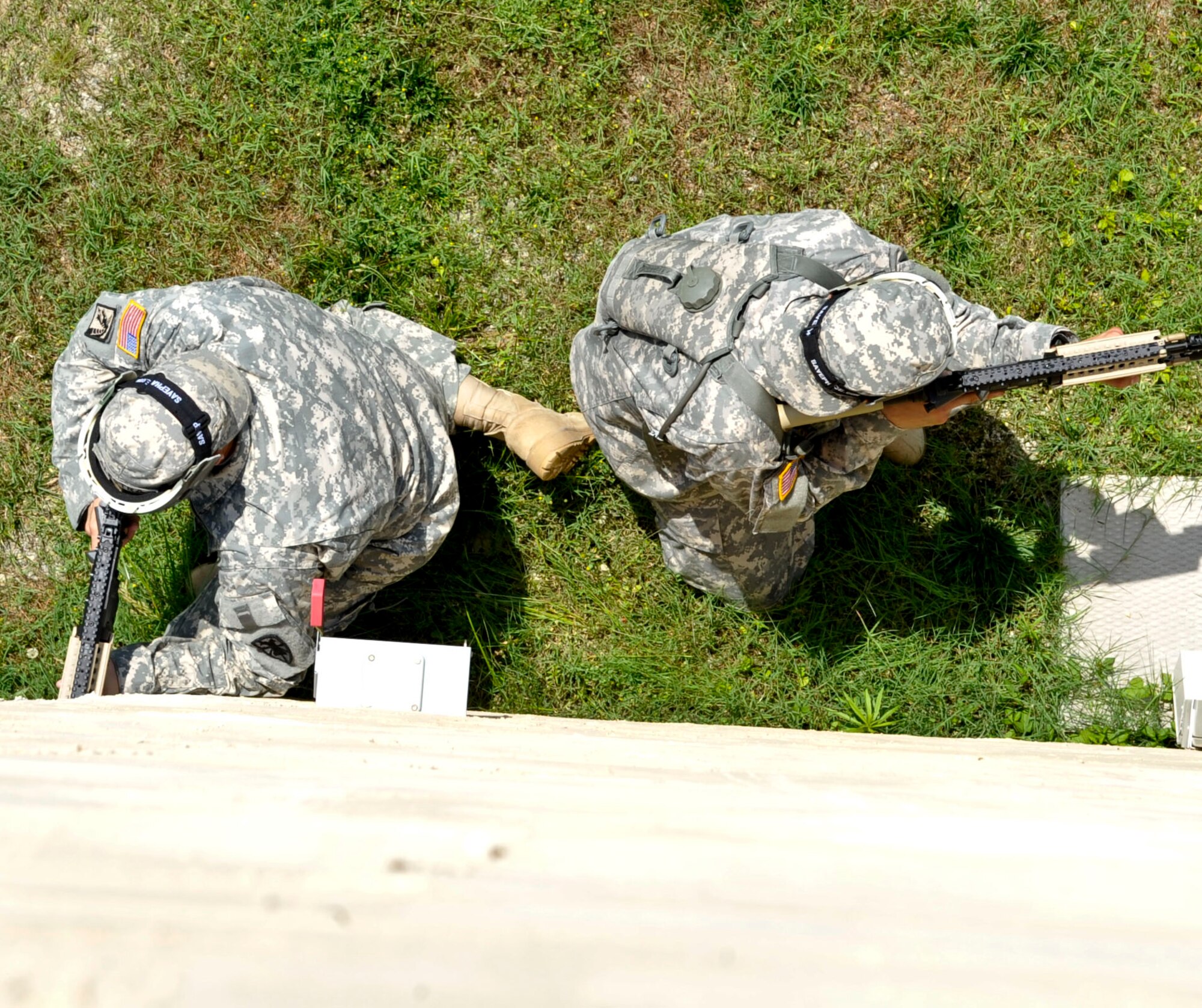 Two Soldiers with the 271st Movement Control Team take cover along the wall of a building during a simulated ambush conducted during a counter improvised explosive device training class at the Naval Weapons Station Yorktown, Va., June 13, 2013. Soldiers underwent three days of intensive training in preparation for an upcoming deployment. (U.S. Air Force photo by Staff Sgt. Wesley Farnsworth / Released) 