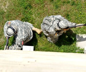 Two Soldiers with the 271st Movement Control Team take cover along the wall of a building during a simulated ambush conducted during a counter improvised explosive device training class at the Naval Weapons Station Yorktown, Va., June 13, 2013. Soldiers underwent three days of intensive training in preparation for an upcoming deployment. (U.S. Air Force photo by Staff Sgt. Wesley Farnsworth / Released) 