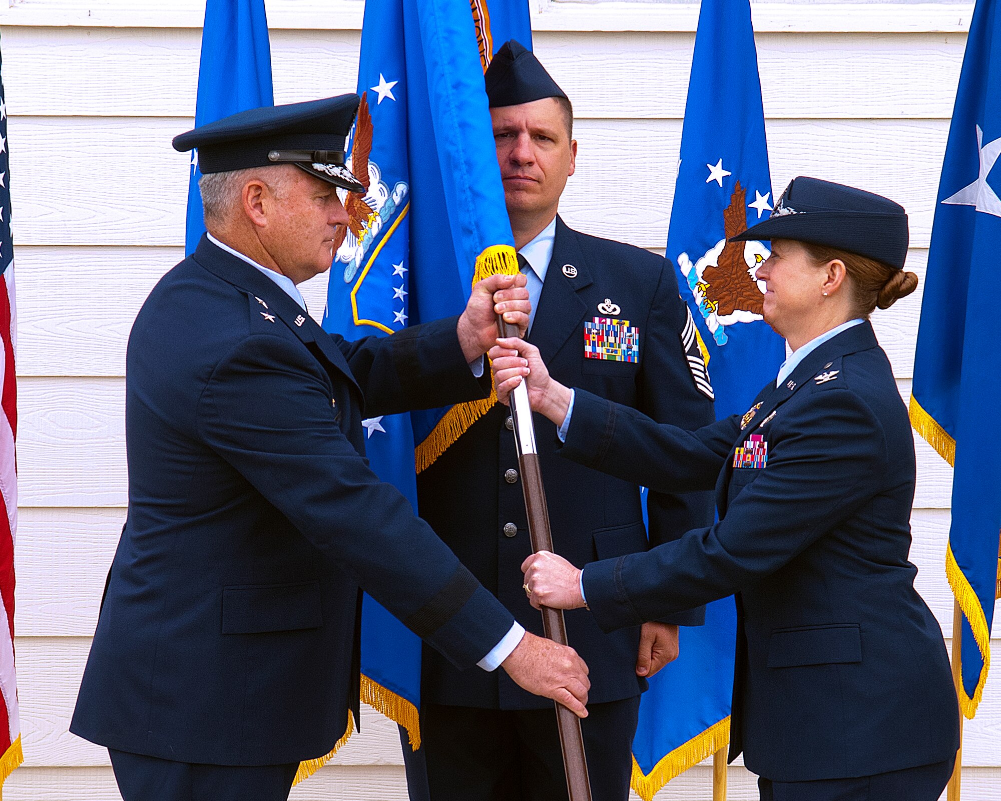Maj. Gen. Michael Carey, 20th Air Force commander passes the 90th Missile Wing flag to Col. Tracey Hayes as she assumes command of the 90th MW during a ceremony on F.E. Warren Air Force Base, June 17. Chief Master Sgt. Michael Garrou, 90th MW command chief stands by to take the flag from Hayes. (U.S. Air Force photo by R.J. Oriez)