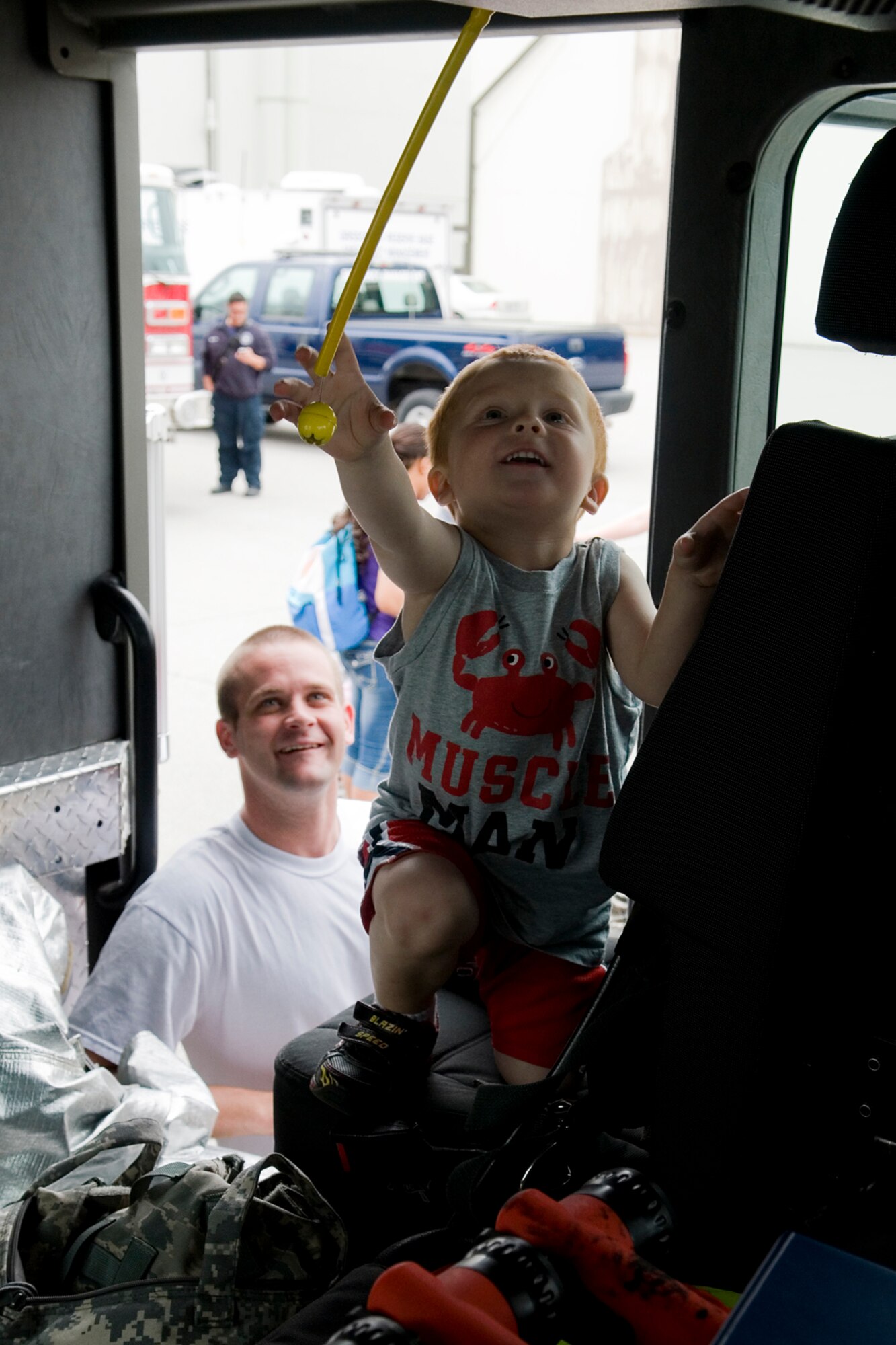 Bryce Navarre stretches for a yellow rope in a fire truck as his father, Staff Sgt. Jeff Navarre, 434th Maintenance Squadron fuel systems specialist, watches closely during Grissom annual Family Appreciation Day here June 1, 2013. Fire trucks were one of the many static displays set up for tours during the event that is held for Grissom Airmen, base personnel and their families. (U.S. Air Force photo/Senior Airman Jami K. Lancette)