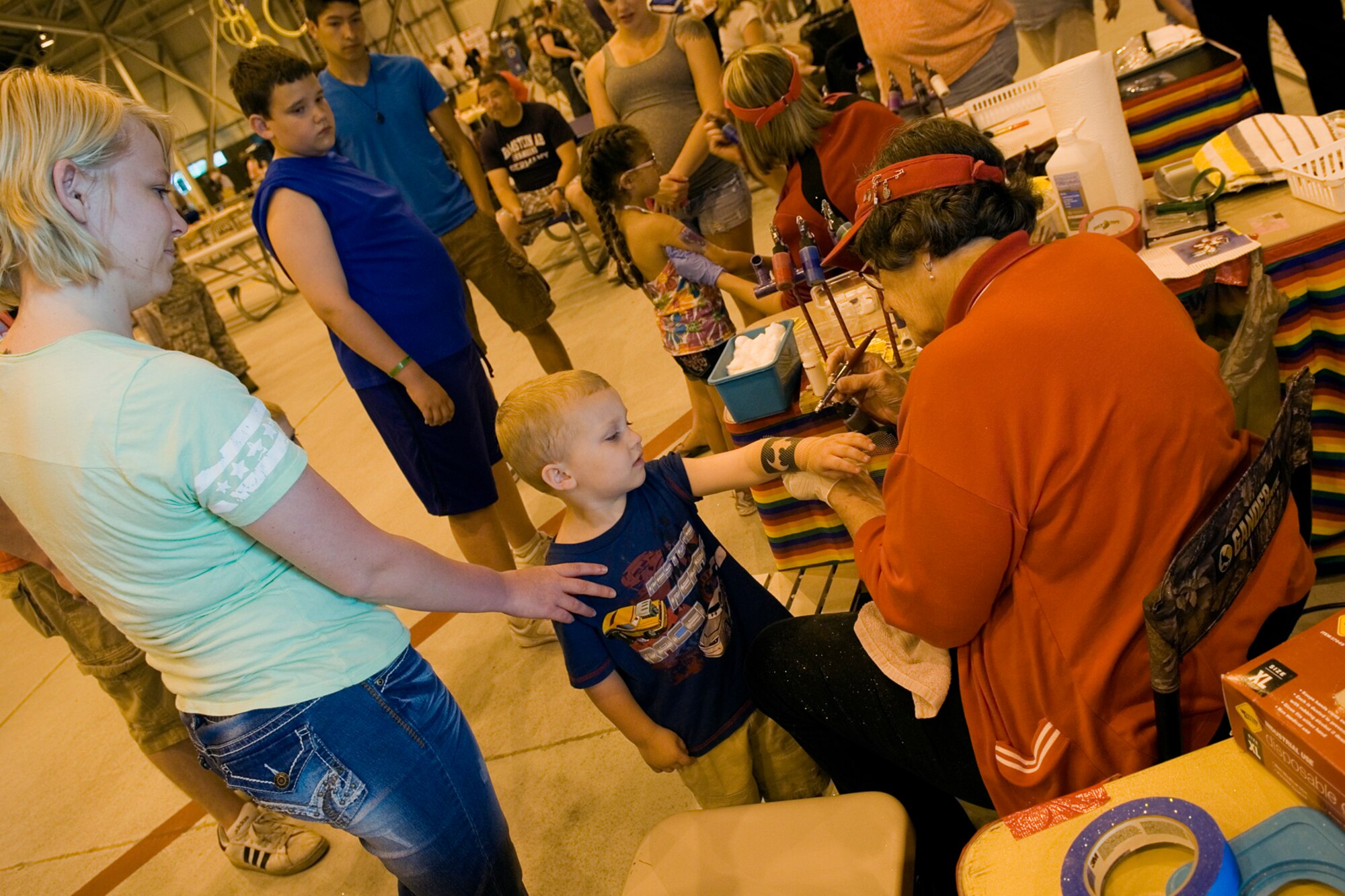 Airman 1st Class Kylee Knebel, 434th Air Refueling Wing financial management apprentice, watches her son, Mason Howell, while Heggie Sikorski sprays on a temporary tattoo during Grissom's annual Family Appreciation Day here June 1, 2013. A face painting station was just many of the booths and events set up for Airmen and their families to enjoy. (U.S. Air Force photo/Senior Airman Jami K. Lancette)