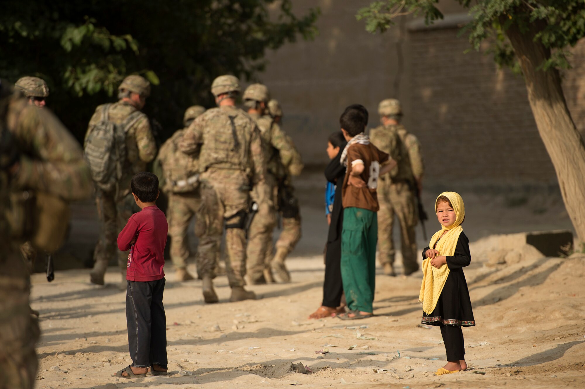 An Afghan girl watches as 455th Expeditionary Security Forces Group airmen establish a security detail from the town of Saka near Bagram Air Field, Afghanistan, June 13, 2013. Security forces airmen teamed up with 577th Expeditionary Prime Base Engineer Emergency Force Squadron pavement and heavy equipment “Dirt Boys” to rebuild a road connecting Saka with Payan Janqadam. (USAF Photo/Master Sgt. Ben Bloker)