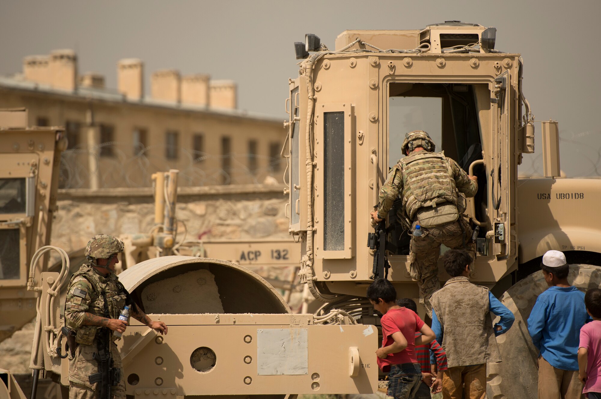 Staff Sgt. Jacob Snellings climbs aboard a vibratory roller as Staff Sgt. Brandon Buffa and Afghan youth look on in the town of Payan Janqadam near Bagram Air Field, Afghanistan, June 13, 2013. Snellings and Buffa, both 577th Expeditionary Prime Base Engineer Emergency Force Squadron pavement and heavy equipment “Dirt Boys,” teamed up with 455th Expeditionary Security Forces Group airmen to rebuild a road connecting Payan Janqadam with Saka. Snellings hails from Cincinnati, Ohio and Buffa hails from St. Louis, Mo. Both are deployed from Holloman Air Force Base, N.M. (USAF Photo/Master Sgt. Ben Bloker)
