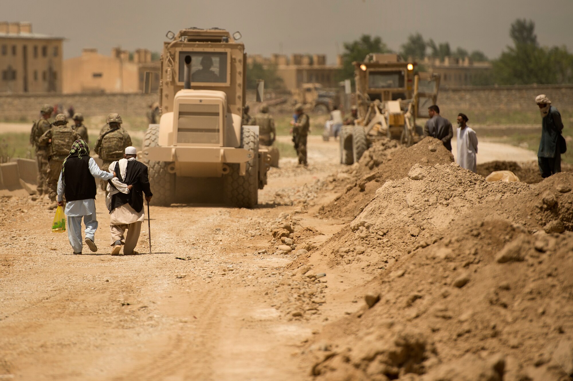 Elderly Afghan men make their way down Route Safe Side as 455th Expeditionary Security Forces Group airmen team up with 577th Expeditionary Prime Base Engineer Emergency Force Squadron pavement and heavy equipment “Dirt Boys” to rebuild the road connecting Payan Janqadam with Saka near Bagram Airf Field, Afghanistan, June 13, 2013. (USAF Photo/Master Sgt. Ben Bloker)