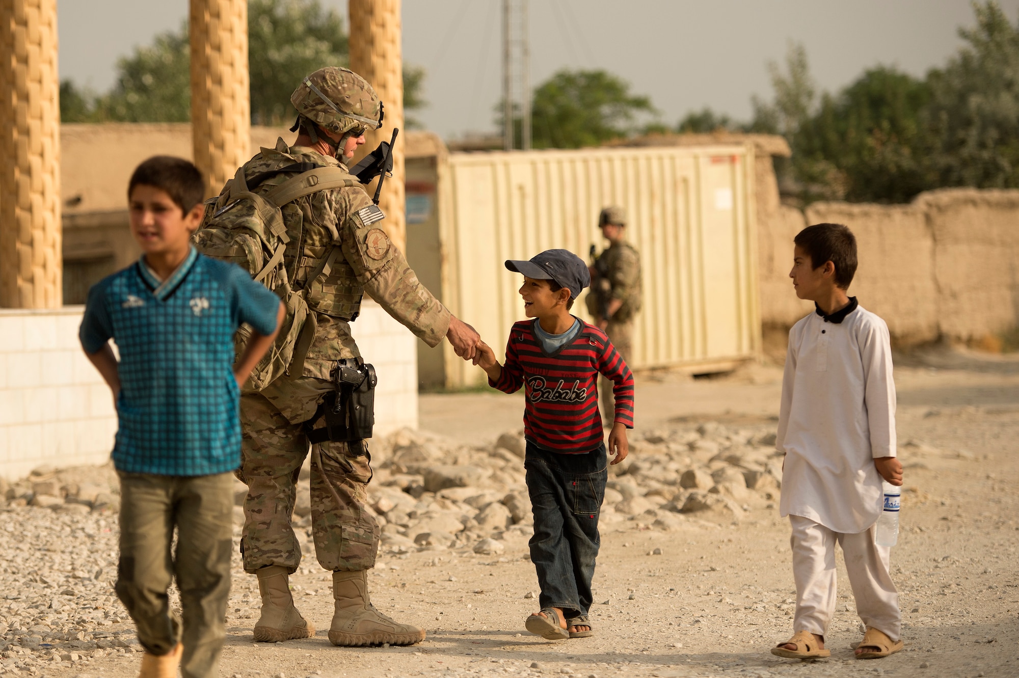 Staff Sgt. Michael Sweeney, 455th Expeditionary Security Forces Group, greets a local Afghan youth during a security detail in the town of Saka near Bagram Air Field, Afghanistan, June 13, 2013. Security forces airmen teamed up with 577th Expeditionary Prime Base Engineer Emergency Force Squadron pavement and heavy equipment “Dirt Boys” to rebuild a road connecting Saka with Payan Janqadam. Sweeney hails from Clovis, Calif., and is deployed from the 144th Fighter Wing, California Air National Guard. (USAF Photo/Master Sgt. Ben Bloker)
