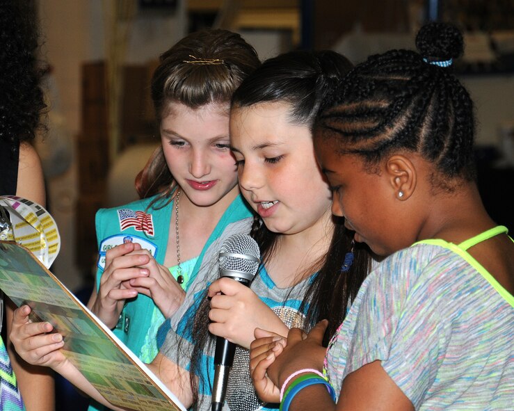 Center, Jade Kuhr, 10, daughter of Joshua Kuhr, 100th Force Support Squadron chief resource manager from Bloomington, Minn., narrates during a charity fashion show June 14, 2013, at RAF Lakenheath, England. Models participating in the fashion show included Girl Scouts and Cub Scouts of various age groups. The girls chose to plan and host a fashion show in order to collect clothing donations for several local charities as well as for the Majengo Children's Home in Tanzania. (U.S. Air Force photo by Gina Randall/Released)
