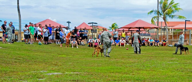 Service members watch as a crowd volunteer participates in a military working demonstration June 14, 2013, during a Dorm Dweller and Deployer Appreciation Day event on Andersen Air Force Base, Guam. The day’s festivities also included a flag football tournament, open use of the base pool, a giant slip and slide, corn-hole toss, ladder golf, hula dance performances and a first sergeant and commander dunk tank. (U.S. Air Force photo by Airman 1st Class Marianique Santos/Released)