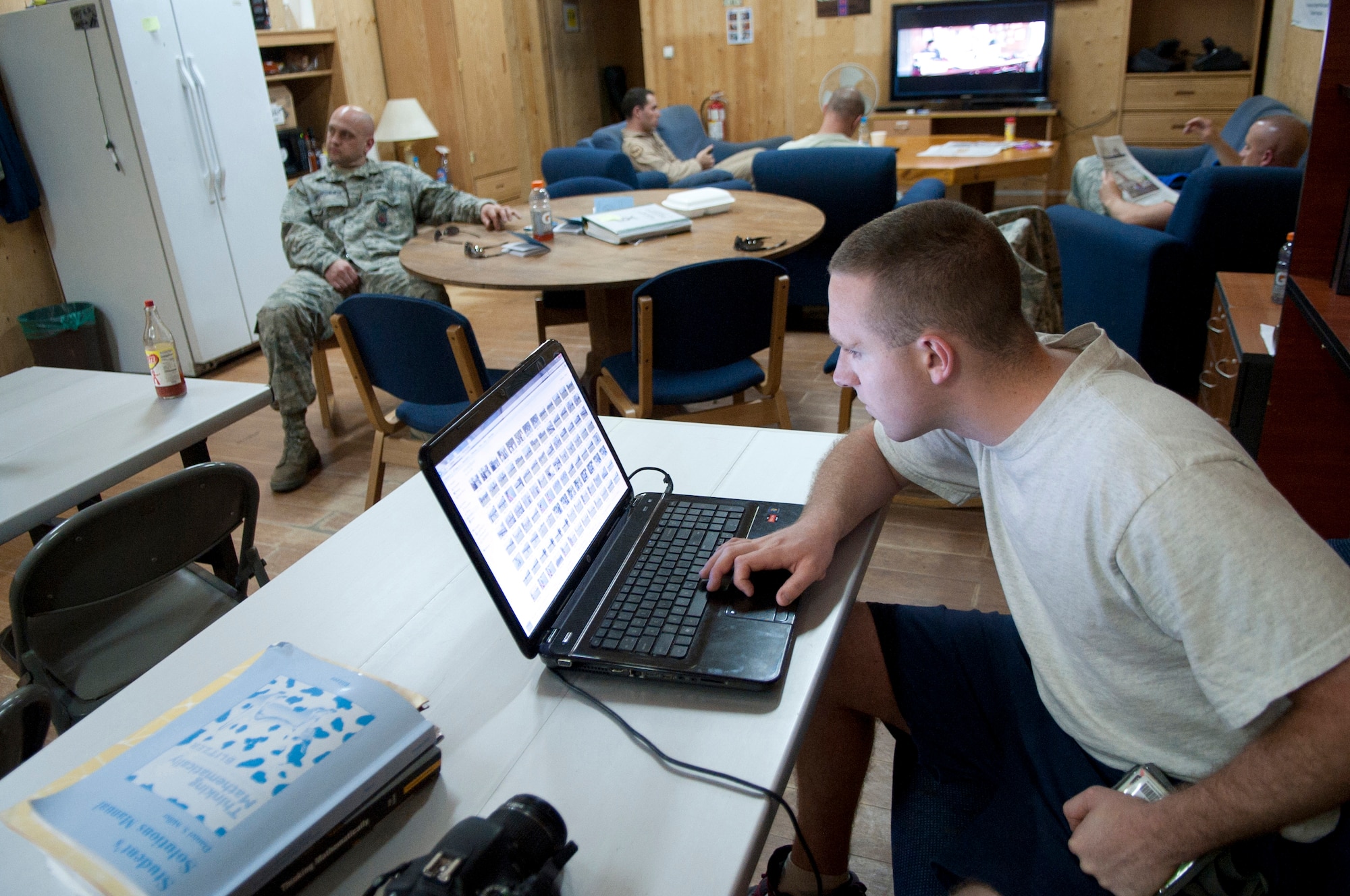 Senior Airman Paul Smith, 376th Civil Engineer Squadron vehicle operator, looks through photos on his laptop while he and other firefighters take advantage of their downtime in a fire station at Transit Center at Manas, Kyrgyzstan, June 12, 2013. Members of the 376th Expeditionary Civil Engineer Squadron take downtime when they can with physical fitness, movies, photography and various forms of creative recreation such as "firehose bowling." Smith is deployed out of Fairchild Air Force Base, Wash., and is a native of Middletown, Del. (U.S. Air Force photo/Staff Sgt. Robert Barnett)