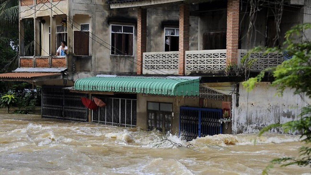 A Thai woman stands at the balcony of her flooded house following torrential rains in Thailand’s southern province of Trang April 2011.  