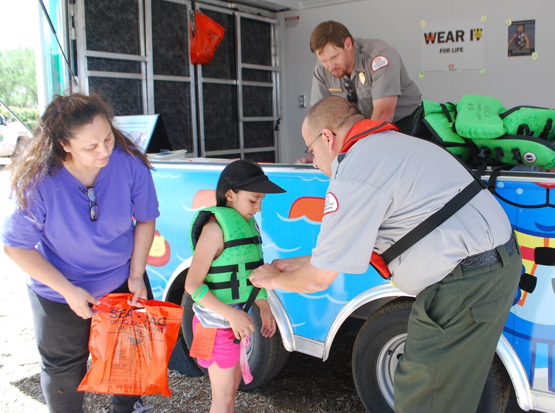 ALBUQUERQUE, N.M., -- Albuquerque District Park Ranger Bob Garcia, Cochiti Lake, shows a young swimmer how a personal flotation device (PFD) should fit properly at the National Get Outdoors Day held at Tingley Beach June 8, 2013. The PFD must be tight enough so it will not come off over a person’s shoulders while strapped together.