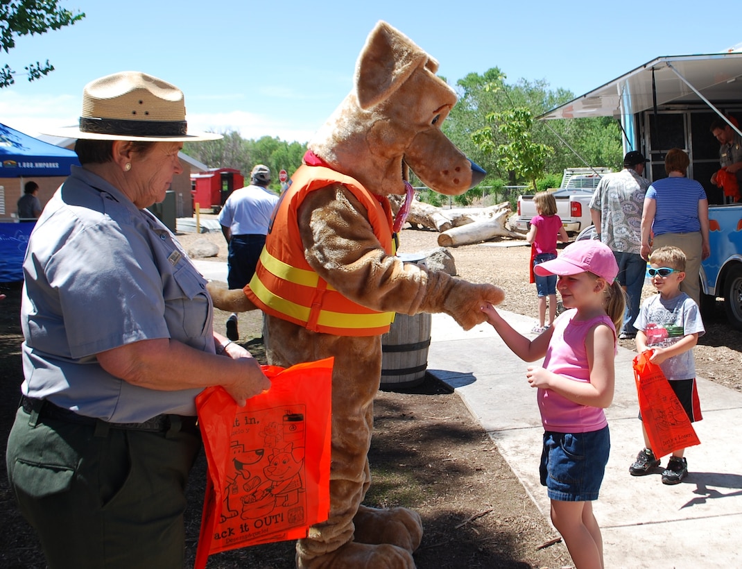 ALBUQUERQUE, N.M., -- Bobber the Water Safety Dog shakes hands with one of the many new friends he made during National Outdoors Day, June 8, 2013.  Kathleen Bennett, outdoor recreation planner with the Albuquerque District, stands by ready to present the child with a bag of water safety goodies.