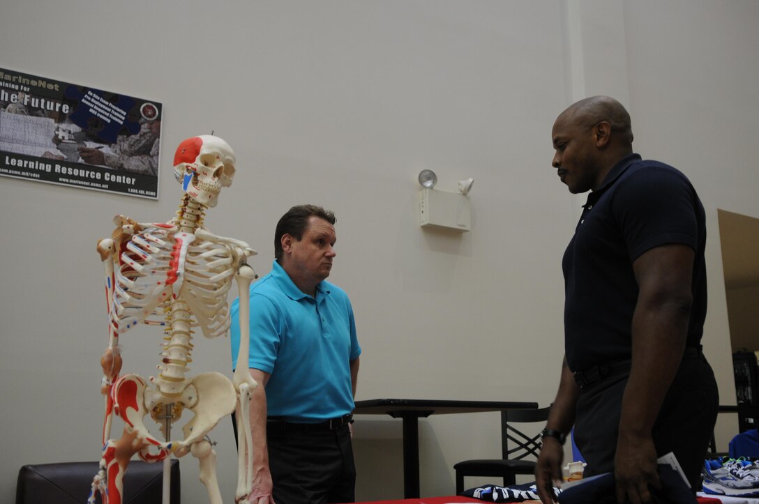 Dr. Jeff Wynn, chiropractor at Naval Health Clinic Quantico, talks about spine care with Rodney Roper, eastern recruiting region facilities manager at Marine Corps Recruiting Command, beside a reminder of the body’s fragile and ephemeral nature. Wynn and other Quantico personnel in the business of health set up injury-prevention information booths at Barber Physical Activity Center on June 12, 2013, to mark men’s health month.