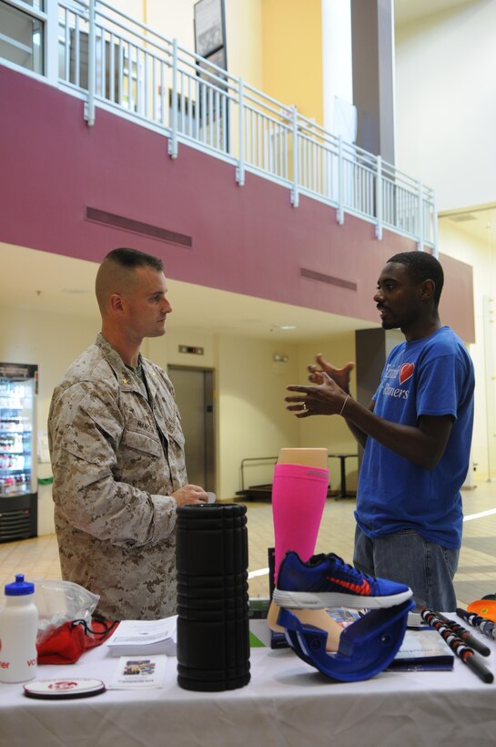 Nate Brooks, director of marketing at VA Runner, discusses footwear with Maj. Patrick Manson on June 12, 2013, at Barber Physical Activity Center, where Brooks and others set up injury-prevention information booths as part of men’s health month. 
