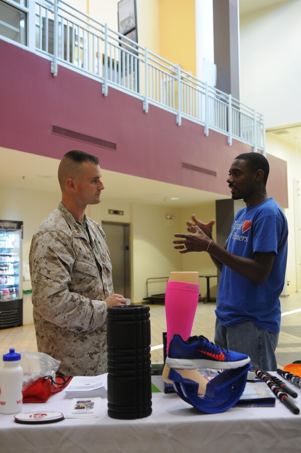 Nate Brooks, director of marketing at VA Runner, discusses footwear with Maj. Patrick Manson on June 12, 2013, at Barber Physical Activity Center, where Brooks and others set up injury-prevention information booths as part of men’s health month. 