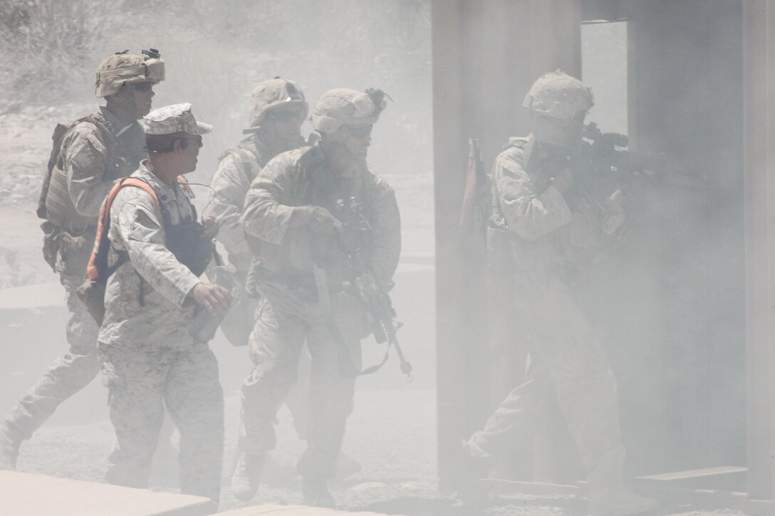 A maneuver coyote with the Tactical Training Exercise Control Group of Marine Corps Air Ground Combat Center Twentynine Palms, Calif., donning orange, provides feedback to infantry Marines with 3rd Battalion, 1st Marine Regiment of Marine Corps Base Camp Pendleton, Calif. during a long range raid training exercise in the desert southeast of Marine Corps Air Station Yuma, Ariz., June 3. The coyotes’ responsibility is to assess and instruct the Marines training for combat.