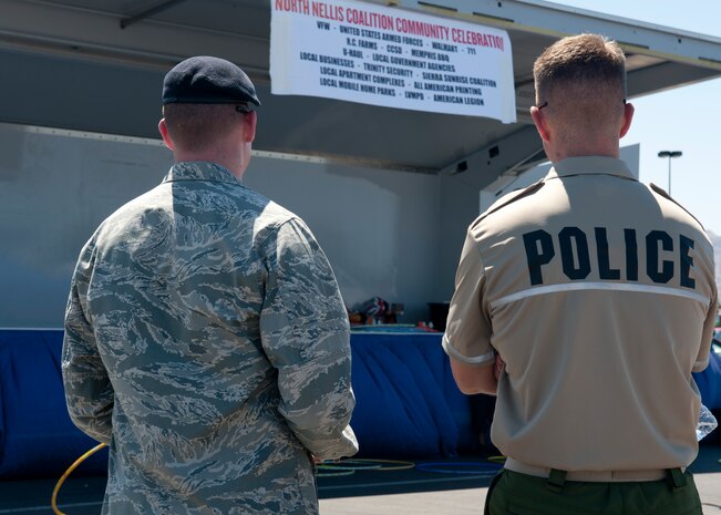 Capt. Arthur Zeitler, 99th Security Forces Squadron force protection officer, and Officer James Paroon, Las Vegas Metro Police Department policeman, stand in front of a stage June 15, 2013, during a North Nellis Coalition community event in North Las Vegas, Nev. Airmen from the 99th SFS joined police officers from the LVMPD to promote safety in the North Las Vegas community. The North Nellis Coalition is a group made up of members from the 99th SFS, the LVMPD and dozens of businesses surrounding Nellis AFB whose purpose is to work together to make the North Las Vegas community safer.  (U.S. Air Force photo by Staff Sgt. Michael Charles) 