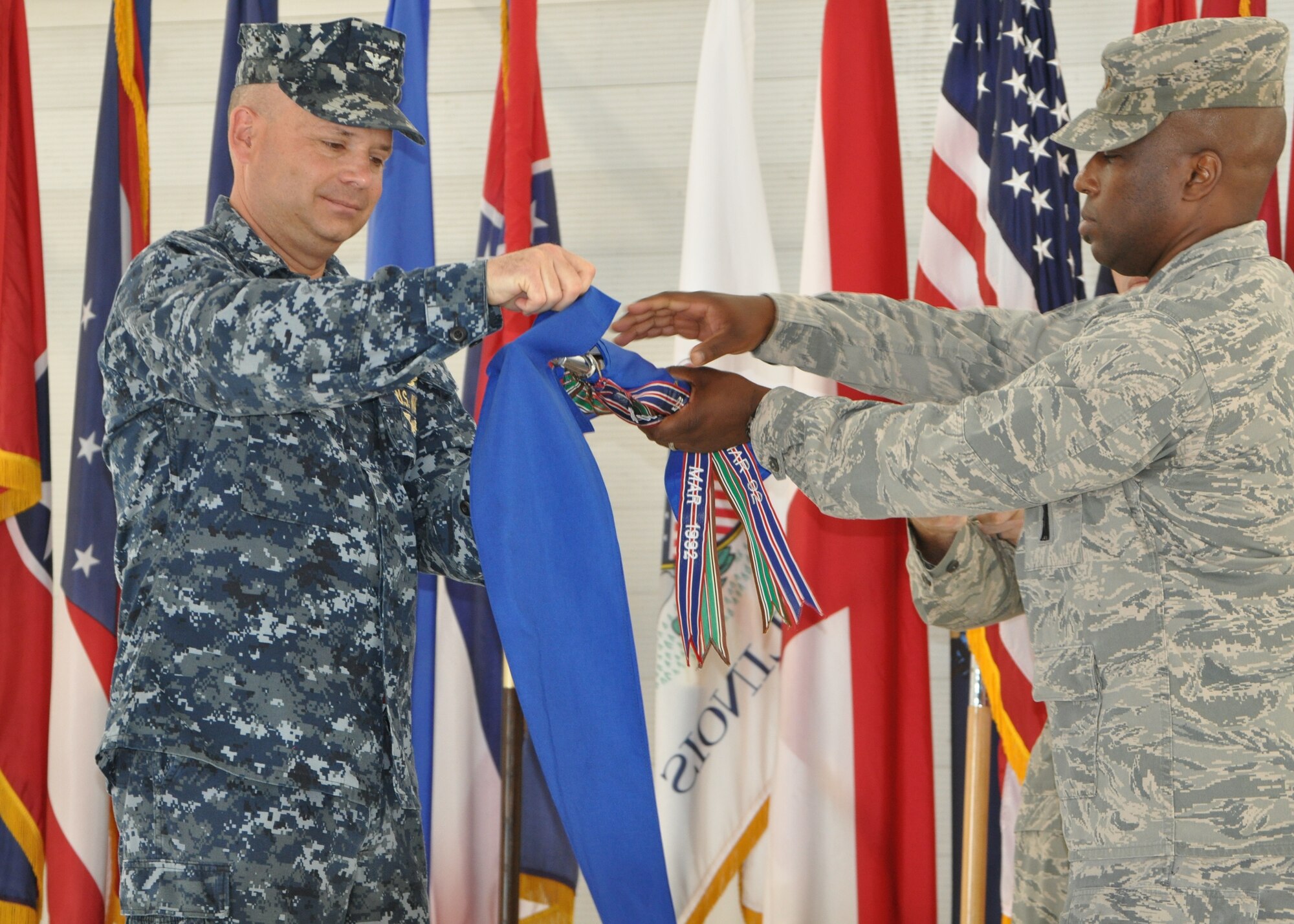Navy Capt. Lance Massey , 33rd Maintenance Group commander, and Maj. Craig Williams, former 33rd MOS commanding officer, cover the 33rd Maintenance Operations Squadron guidon during the unit's inactivation ceremony June 13. The 33rd MOS retired its colors as the result of a service decision last year to reorganize and more efficiently utilize maintenance officers throughout the service. (U.S. Air Force photo/Staff Sgt. Nicholas Egebrecht)