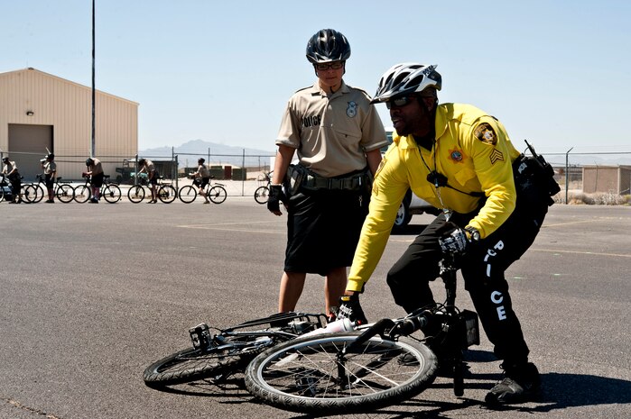U.S. Air Force Airman 1st Class Cinthia Guzman, 99th Security Forces patrolman, watches as Las Vegas Metro Police Department Patrol Sgt. Kendall Bell demonstrates how to pick up a bike and stay alert to surroundings June 19, 2013, behind Bldg. 1100 on Nellis Air Force Base, Nev. More than 20 Airmen from the 99th Security Forces Squadron have been taking part in a Bike Patrol Course which will culminate in testing and certification June 21. (U.S. Air Force photo by Senior Airman Daniel Hughes)  