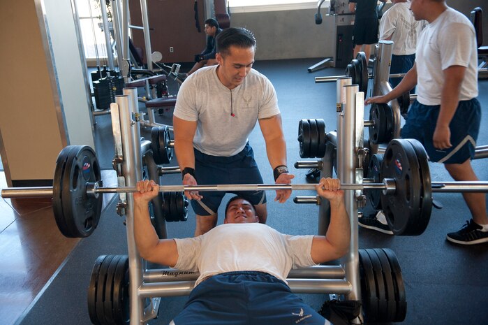Victor Dioguino, 99th Logistics Readiness Squadron vehicle maintenance journeyman, spots Matthew McLaughlin, 99th LRS vehicle maintenance journeyman, as he lifts weights at the Warrior Fitness Center on Nellis Air Force Base, Nev.,  June 17, 2013.The fitness center has free weights and weight lifting machines on the first floor. (U.S. Air Force Photo by Caitlin Kenney)