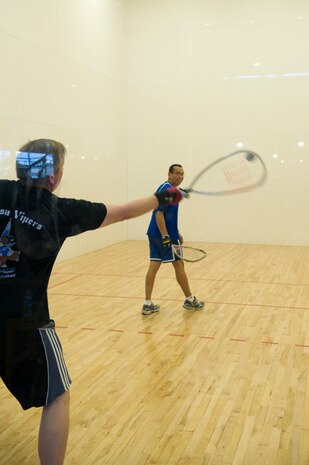 Juan Santos, 99th Logistics Readiness Squadron Nellis Support Center superintendent, looks back as Chris Goff, 99th LRS NSC lodging coordinator, hits a racquetball at the Warrior Fitness Center at Nellis Air Force Base, Nev., June 14, 2013. The racquetball courts are available for use as are equipment rentals at the front desk. The racquetball courts can be reserved for an hour long time slots but are usually first come first serve. (U.S. Air Force Photo by Caitlin Kenney)