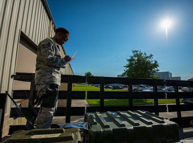 Staff Sgt. Theresa Davis, 628th Logistics Readiness Squadron Individual Protective Equipment technician, checks to make sure the serial numbers in the M-16 cases match her roster before transporting M-16 rifles to Airmen at the 628th Security Forces Squadron Combat Arms Training for an inspection June 13, 2013, at Joint Base Charleston, S.C. Davis is armed with an M-9 pistol since she will be escorting the weapons to the CATAM building. (U.S. Air Force photo/ Senior Airman Dennis Sloan)