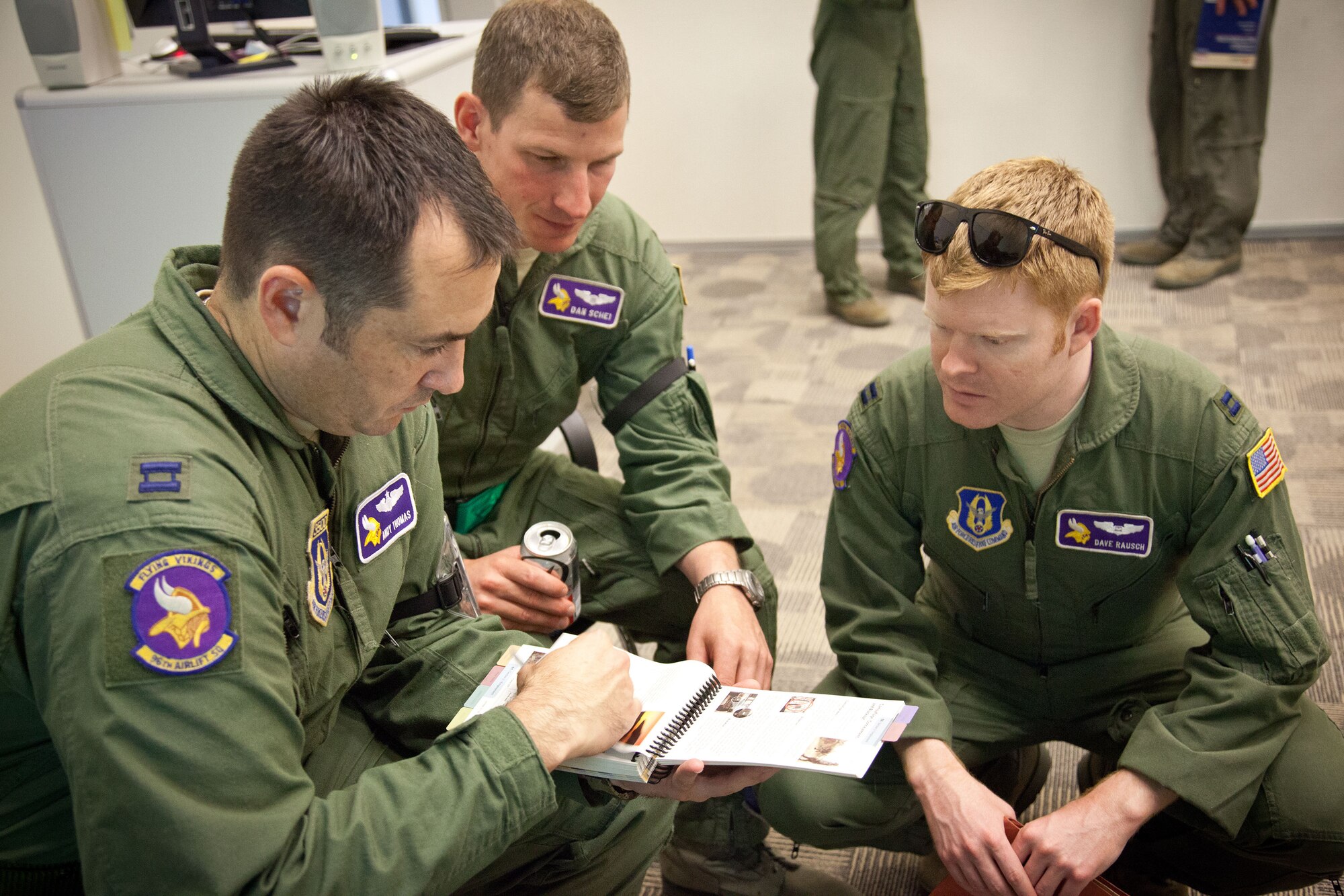 Capts. Andrew Thomas, Daniel Schei, and David Rausch, 96th Airlift Squadron, read up on how to construct a bunker outside the Special Operations Center.  Members of the 934th Airlift Wing participated in an Operational Readiness Exercise during the week of June 17-21 at the Minneapolis-St. Paul Air Reserve Station, Minn.  (U.S. Air Force photo/Shannon McKay)