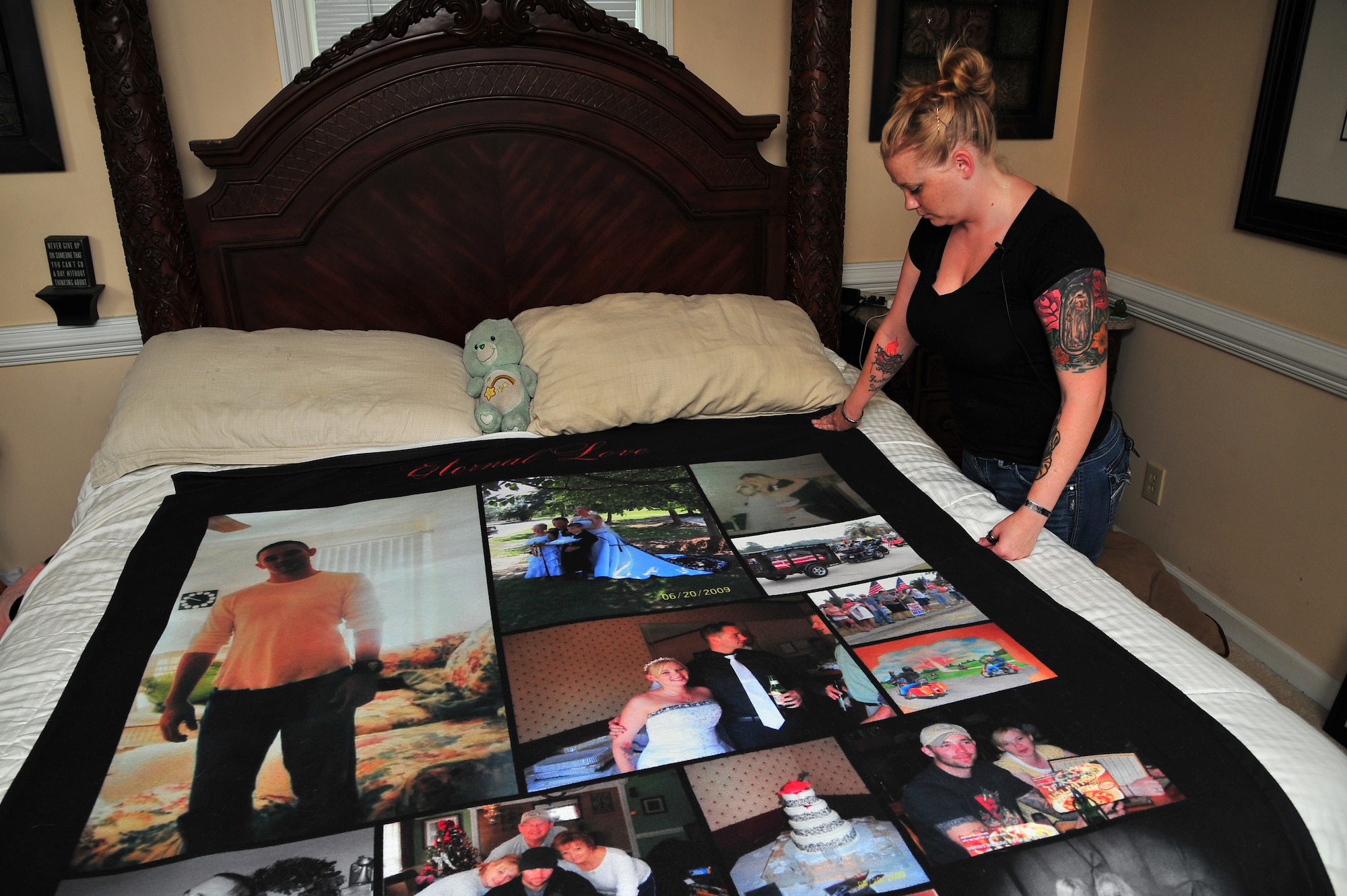 U.S. Air Force Staff Sgt. Kimberly Pate, 4th Civil Engineer Squadron explosive ordnance disposal (EOD)  NCO in-charge of operations, smoothes out a photo blanket on her bed at her home in Kinston, N.C., June 12, 2013. The blanket, given as a gift from her sister, contains Pate’s favorite photos of her and her late husband. (U.S. Air Force photo by Airman 1st Class Aubrey White/Released)