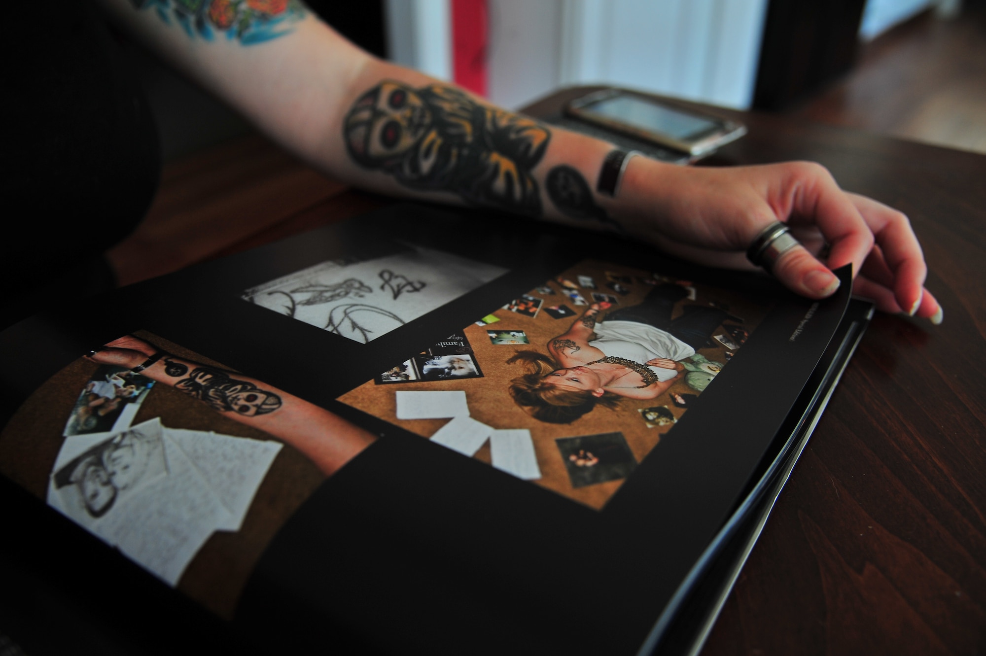 U.S. Air Force Staff Sgt. Kimberly Pate, 4th Civil Engineer Squadron explosive ordnance disposal (EOD)  NCO in-charge of operations, flips through a book of EOD Service member tattoo stories and photos at her home in Kinston, N.C., June 12, 2013. In the book, Pate displayed several of her tattoos which match those of her late husband. Both she and her husband got matching cartoon bomb tattoos to represent their careers in EOD. (U.S. Air Force photo by Airman 1st Class Aubrey White/Released)