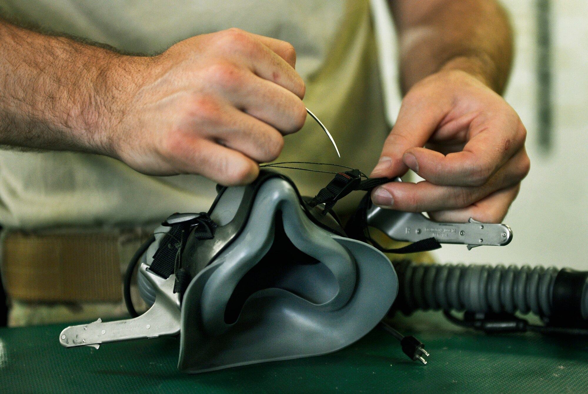 Senior Airman Sean Crowell, 74th Expeditionary Fighter Squadron aircrew flight equipment technician, uses waxed thread to secure an oxygen mask to a pilot’s helmet to ensure it fits correctly while at Bagram Airfield, Afghanistan, June 17. If equipment does not fit properly the pilots display will be out of alignment and the effectiveness of the A-10 pilot’s mission will be degraded. Crowell is a native of Kalamazoo, Mich.(U.S. Air Force photo/ Staff Sgt.Stephenie Wade)