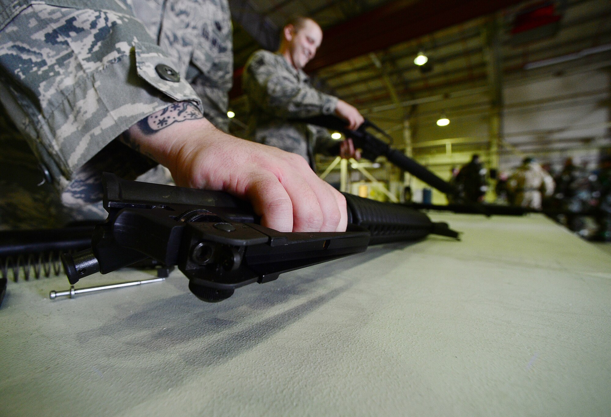 ROYAL AIR FORCE LAKENHEATH, England – Staff Sgt. John Gannon, 48th Security Forces Squadron NCO in charge of Supply (left), picks up a piece of an M-16 while Staff Sgt. Corey Morrow, 48th SFS Assistant NCO in charge of armory (right), clears an M-16, during the Ability to Survive and Operate Rodeo in Hangar 7 June 17, 2013. ATSO training provided Airmen readiness training in preparation for the Phase II exercise. (U.S. Air Force photo by Senior Airman Tiffany M. Grigg)