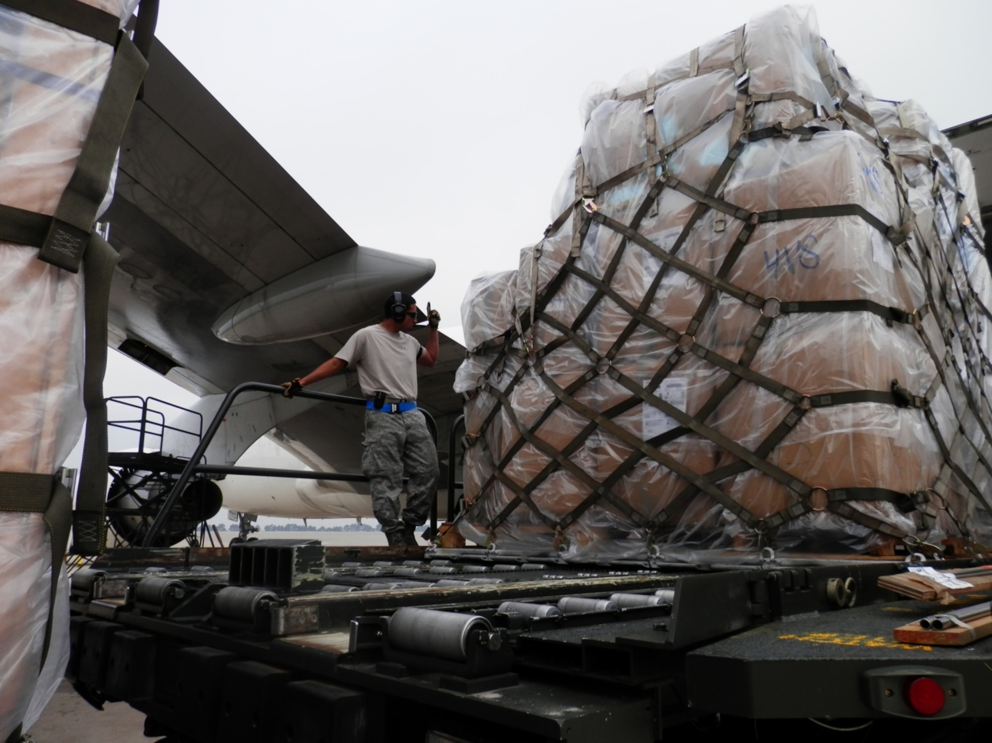 Airman 1st Class Roberto Rodriguez, 731st Air Mobility Squadron aircraft services technician, uses hand signals to communicate with a cargo operator as they raise cargo to a 747B aircraft at Kunsan Air Base, Republic of Korea.  The 731st AMS had to transition air freight operations to Kunsan for a projected two-month partial runway closure. (Air Force courtesy photo/Master Sgt. David Hardy)