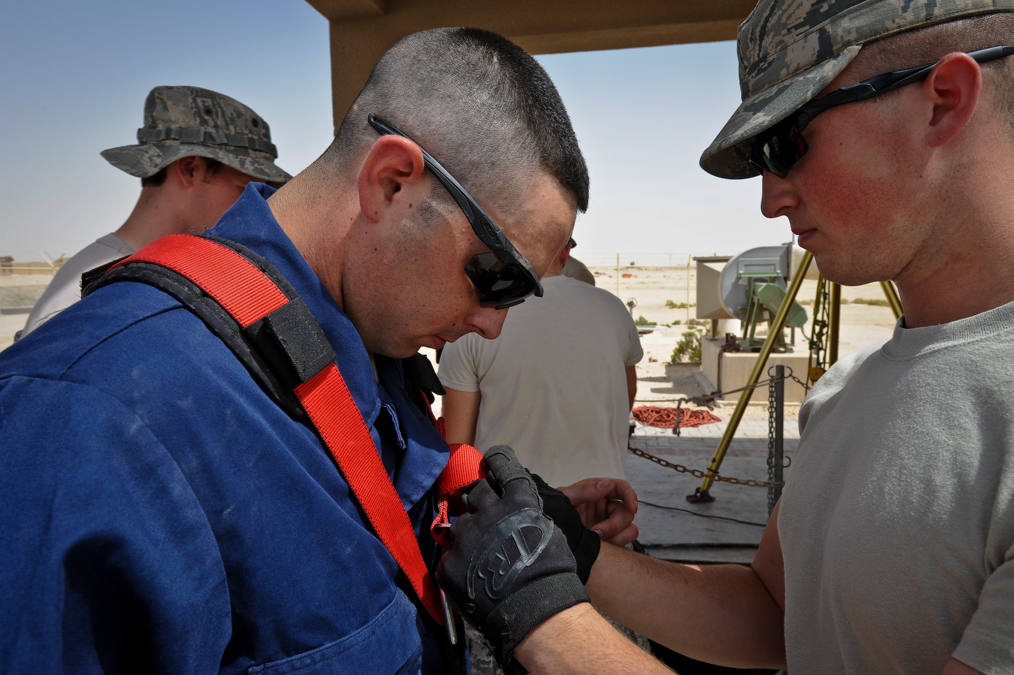Senior Airman Joshua Paul straps a harness onto Airman 1st Class Devin Walsh as the team prepares to fix a broken sewage lift station pump at the 379th Air Expeditionary Wing in Southwest Asia, June 18, 2013. Paul is a 379th Expeditionary Civil Engineer Squadron firefighter deployed from Andrews Air Force Base, Md., and Walsh is a 379th ECES water and fuel systems maintenance technician deployed from Elmendorf AFB, Alaska. (U.S. Air Force photo/Senior Airman Benjamin Stratton)
